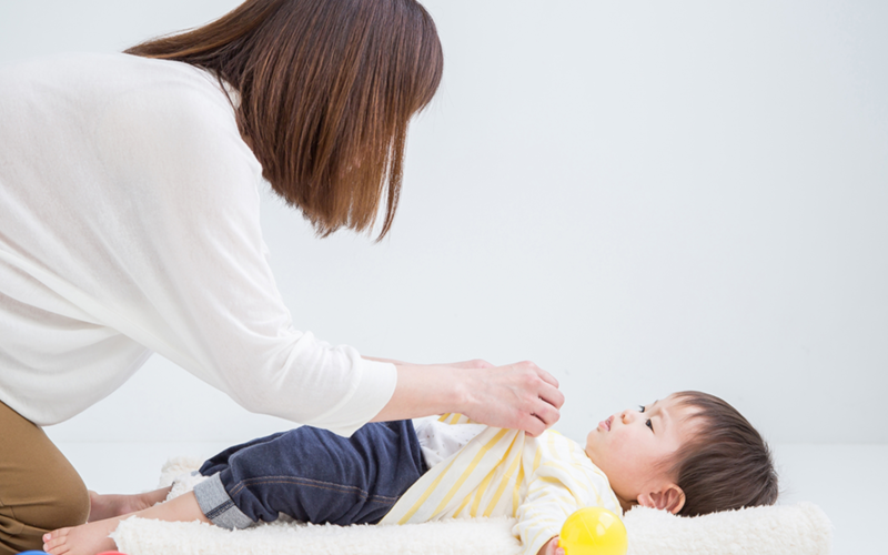 子どもを着替えさせるお母さん